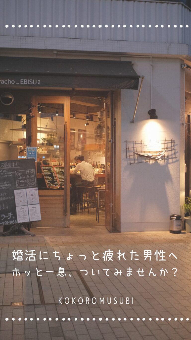 夜のカフェの前で、一人で座る男性の後ろ姿が見える落ち着いた風景。 「婚活にちょっと疲れた男性へ ホッと一息、ついてみませんか？ KOKOROMUSUBI」というメッセージが添えられ、婚活疲れの男性に向けたやさしい励ましの一枚。