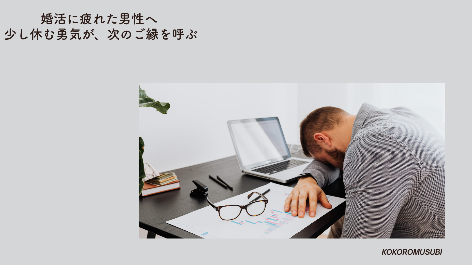 ノートパソコンの前で机にうつ伏せる男性。婚活に疲れた男性が、心を休めている様子を表現したイメージ。横には眼鏡と書類が置かれている。